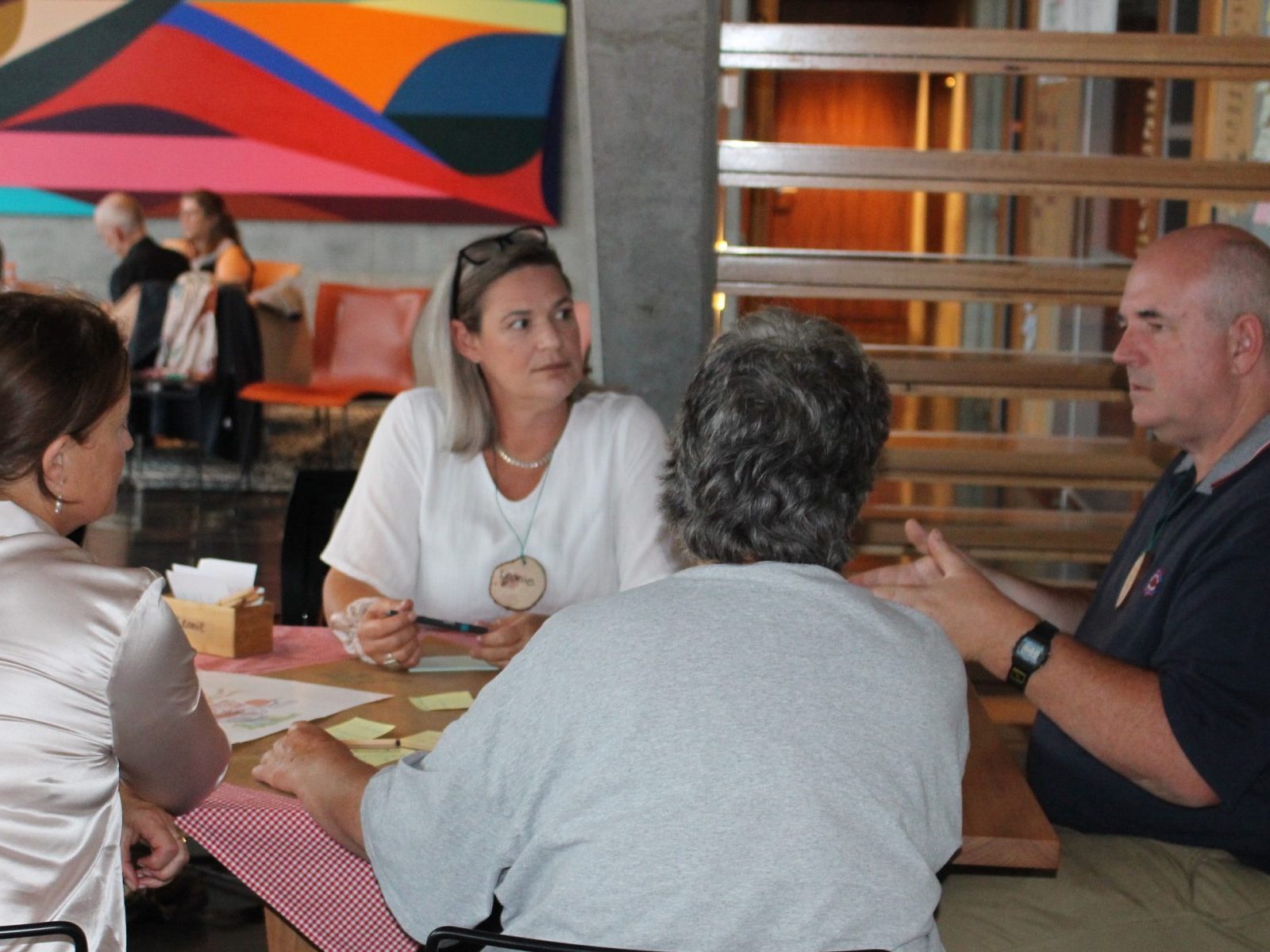 a group of people in discussion around a table with post it notes